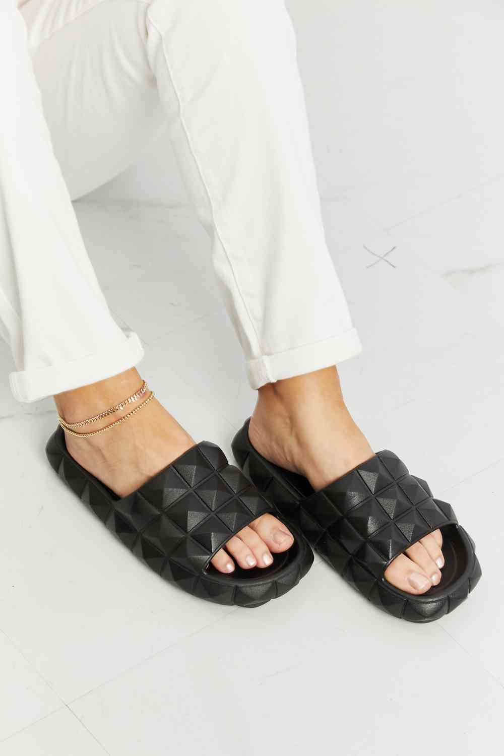 Studded black slide sandal detail showing open toe and stud embellishment