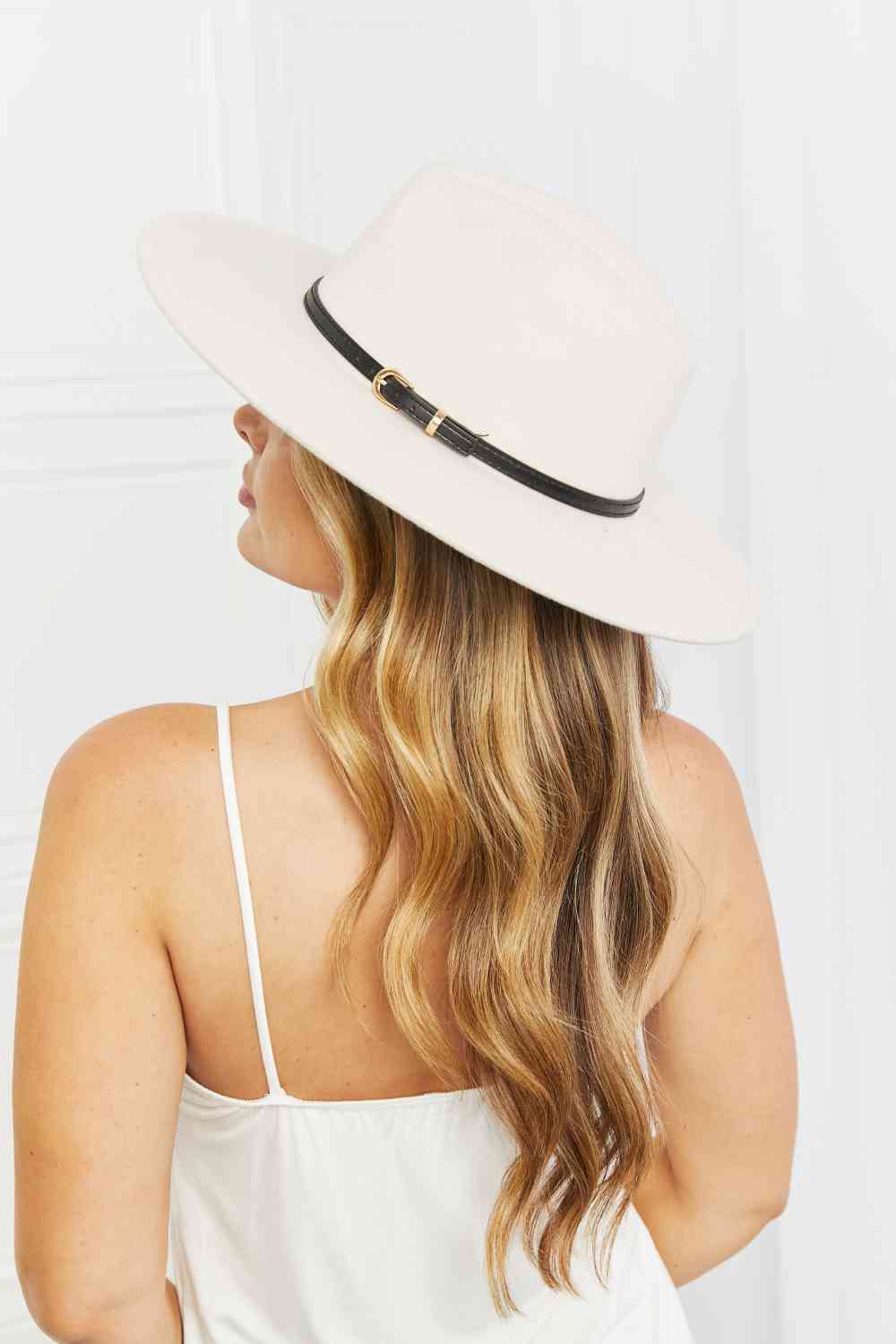 Beige fedora hat with thin black belt and gold buckle detail, side view