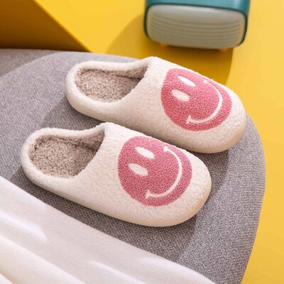 White and pink smiley face slippers styled on feet at home